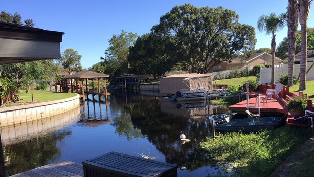 A calm water body with a dock, a covered seating area, and a small boat. - Look Promo DEALS, Resort Like Waterfront, Orlando 4/2 Home, Private Pool, Dock (Orlando)