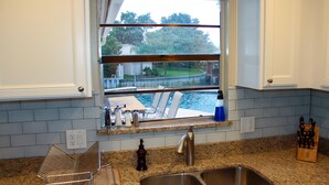A kitchen with a window overlooking a dock and water, a stainless steel sink, and a granite countertop. - Look Promo DEALS, Resort Like Waterfront, Orlando 4/2 Home, Private Pool, Dock (Orlando)