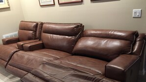 A brown leather sofa with a reclining mechanism, positioned in a room with a light-colored floor and a framed picture on the wall. - Look Promo DEALS, Resort Like Waterfront, Orlando 4/2 Home, Private Pool, Dock (Orlando)