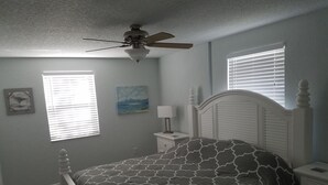 A bedroom with a bed, a nightstand, a ceiling fan, a window with blinds, and a wall-mounted picture. - Beautiful Beach House 🏖 Few steps from the beach 👣 (Ormond Beach)
