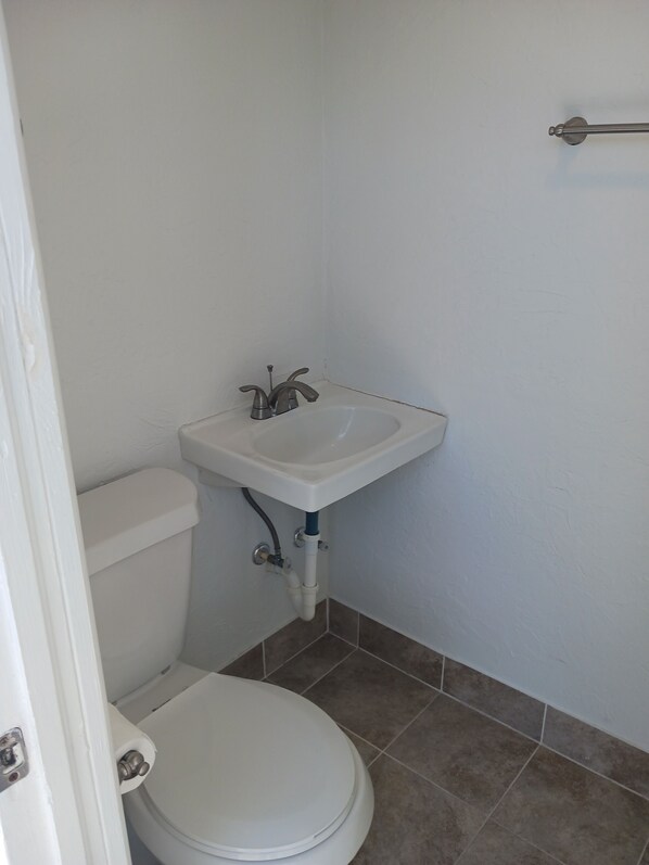 Un bagno piccolo con un water bianco, un lavandino bianco e un porta asciugamani.