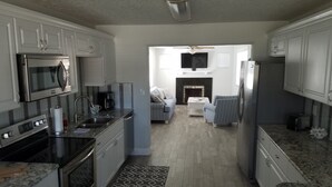 A modern kitchen with white cabinets, stainless steel appliances, and a central island. - Beautiful Beach House 🏖 Few steps from the beach 👣 (Ormond Beach)