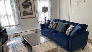 A living room with a blue sofa, patterned cushions, a coffee table, and a rug.
