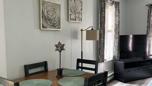 A dining area with a wooden table and chairs, a star-shaped decoration, and two framed floral artworks on the wall.