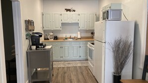 A kitchen with light blue cabinets, a microwave, a refrigerator, and a coffee maker.