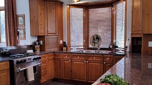 Una cucina con mobili in legno, un fornello, un lavello e una finestra con persiane.