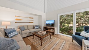 Ett vardagsrum med en soffa, ett soffbord, en tv och ett stort fönster.