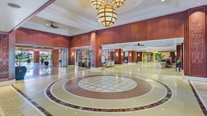 Eine geräumige Lobby mit einem kreisförmigen Fußbodenmuster, Holzvertäfelung und einem zentralen Kronleuchter.