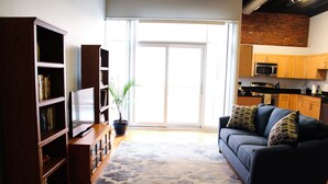 A living room with a dark sofa, a television, and wooden bookshelves.