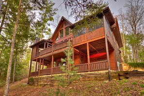 A wooden cabin with a balcony and a red awning, surrounded by trees. - Reel Creek Lodge - Fightingtown Creek (Blue Ridge)