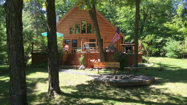 A wooden cabin with a porch, a flag, and a sign reading "Paul Bunyan Trail". - Log Cabin on Garfield Lake near Walker MN (Laporte)