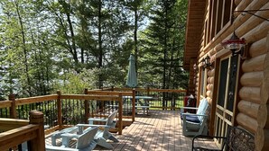A wooden deck with Adirondack chairs and a table, surrounded by trees. - Log Cabin on Garfield Lake near Walker MN (Laporte)