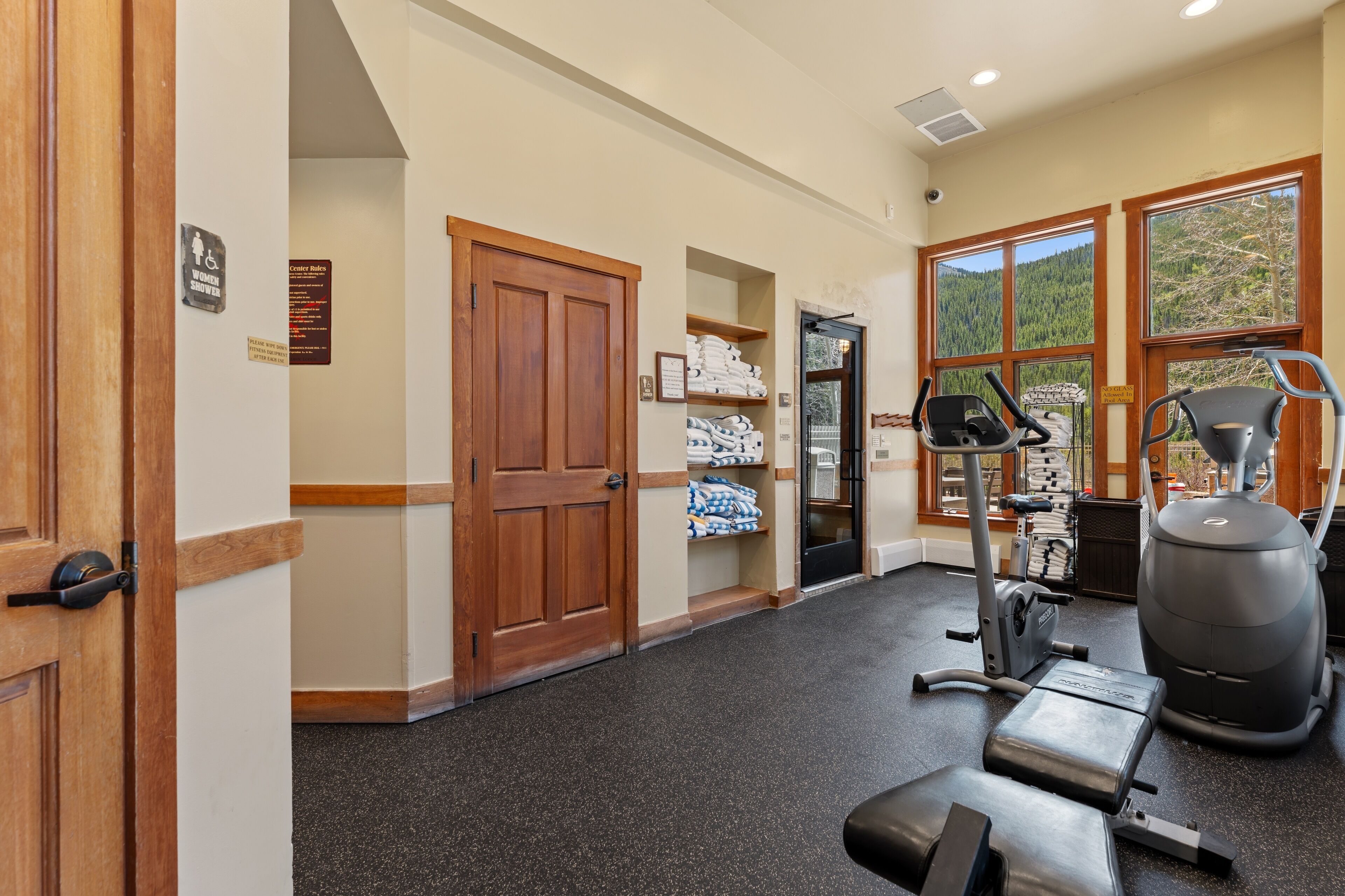 A gym with exercise equipment, a door with a sign, and a window with a view.