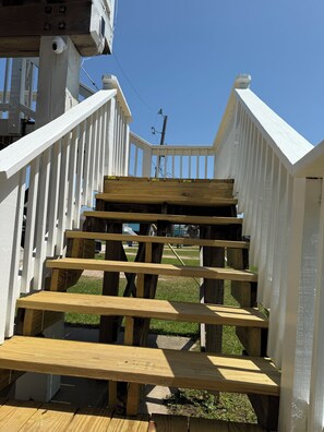 Un escalier en bois avec des rampes blanches menant à une terrasse.