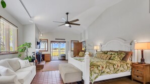 Um quarto espaçoso com uma cama grande, um ventilador de teto e vista para o exterior por uma porta de correr.