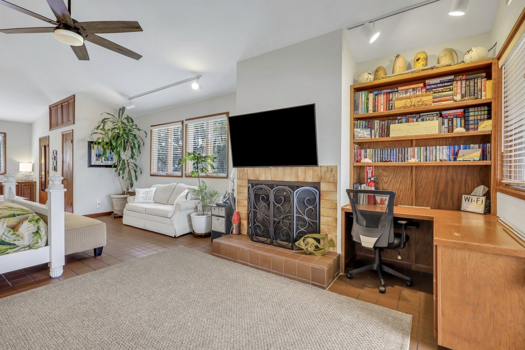 A living room with a fireplace, a bookshelf, a television, and a desk with a chair.