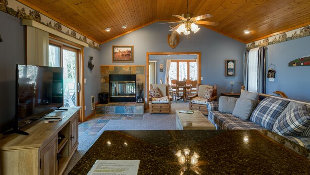 A spacious living room with a large wooden ceiling, a fireplace, a dining area, and a sofa. - RELAX & GETAWAY IN A FULY FURNISHED CABIN IN THE BLUE RIDGE SMOKEY MOUNTAINS.  (Maggie Valley)