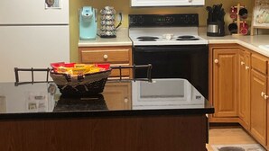 A kitchen with wooden cabinets, a white refrigerator, a microwave, a stove, and a coffee maker. - RELAX & GETAWAY IN A FULY FURNISHED CABIN IN THE BLUE RIDGE SMOKEY MOUNTAINS.  (Maggie Valley)