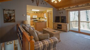 A cozy living room with a plaid sofa, a wooden coffee table, and a television. - RELAX & GETAWAY IN A FULY FURNISHED CABIN IN THE BLUE RIDGE SMOKEY MOUNTAINS.  (Maggie Valley)