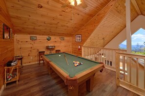 Enjoy a game of pool in this room with a pool table and sloped ceiling.