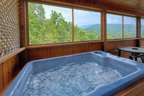 Relax in a spacious room with a large hot tub and a serene forest view.