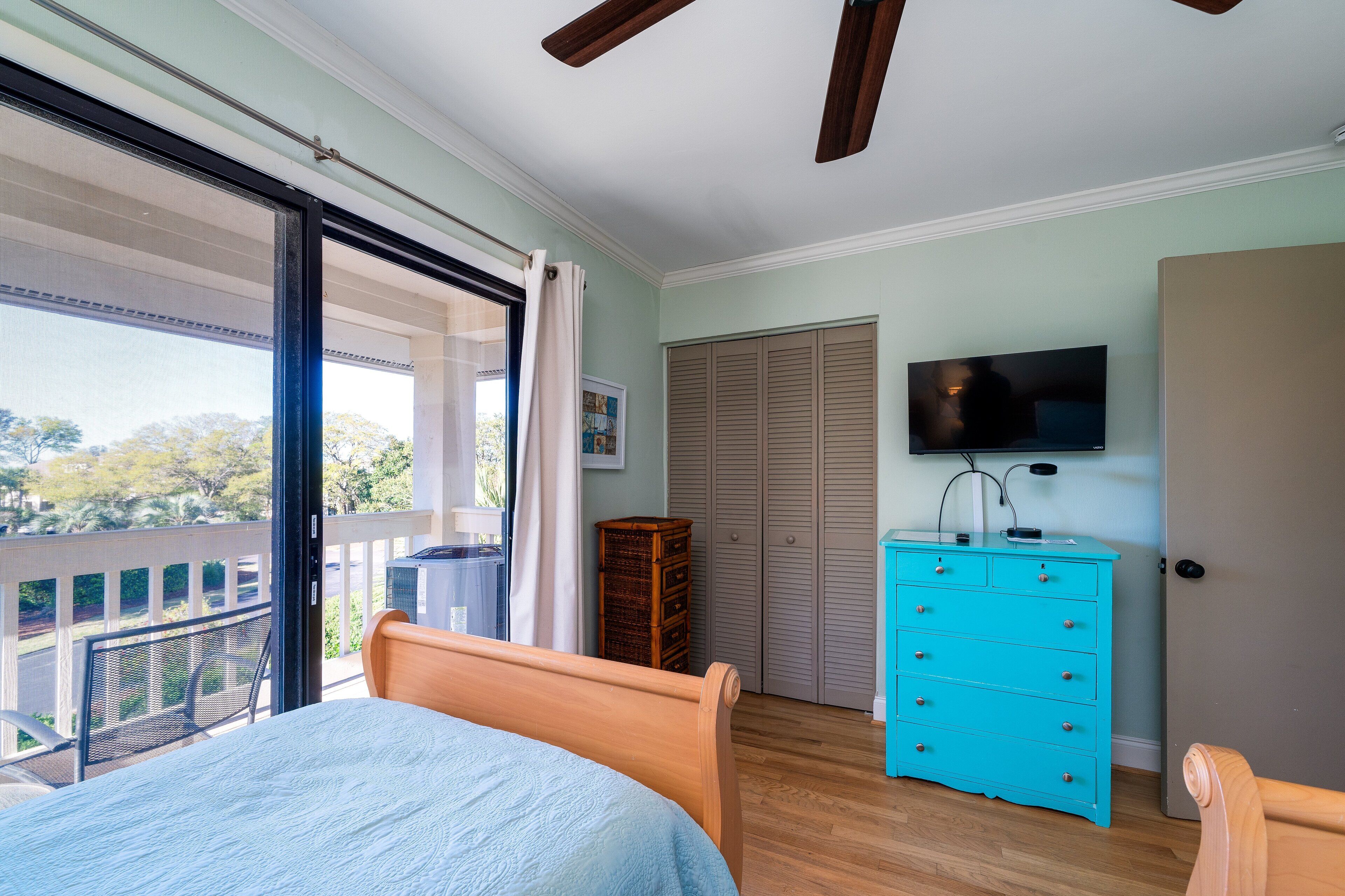 Une chambre avec un lit, une commode, une télévision et un balcon offrant une vue.
