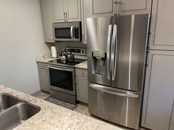 A kitchen with stainless steel appliances, including a refrigerator, oven, and microwave.