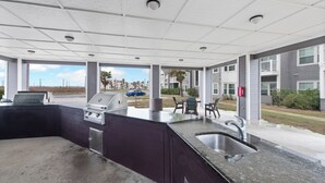 Una cocina exterior moderna con una parrilla, un lavamanos y una zona de estar.