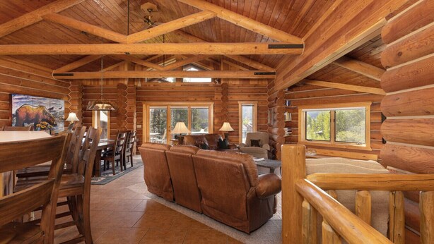 Ein rustikales Holzhaus im Inneren mit Essbereich, Sofa und Fenstern.