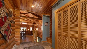 Ein rustikales Holzhaus im Inneren mit Essbereich, einer Treppe und einer Holztür.