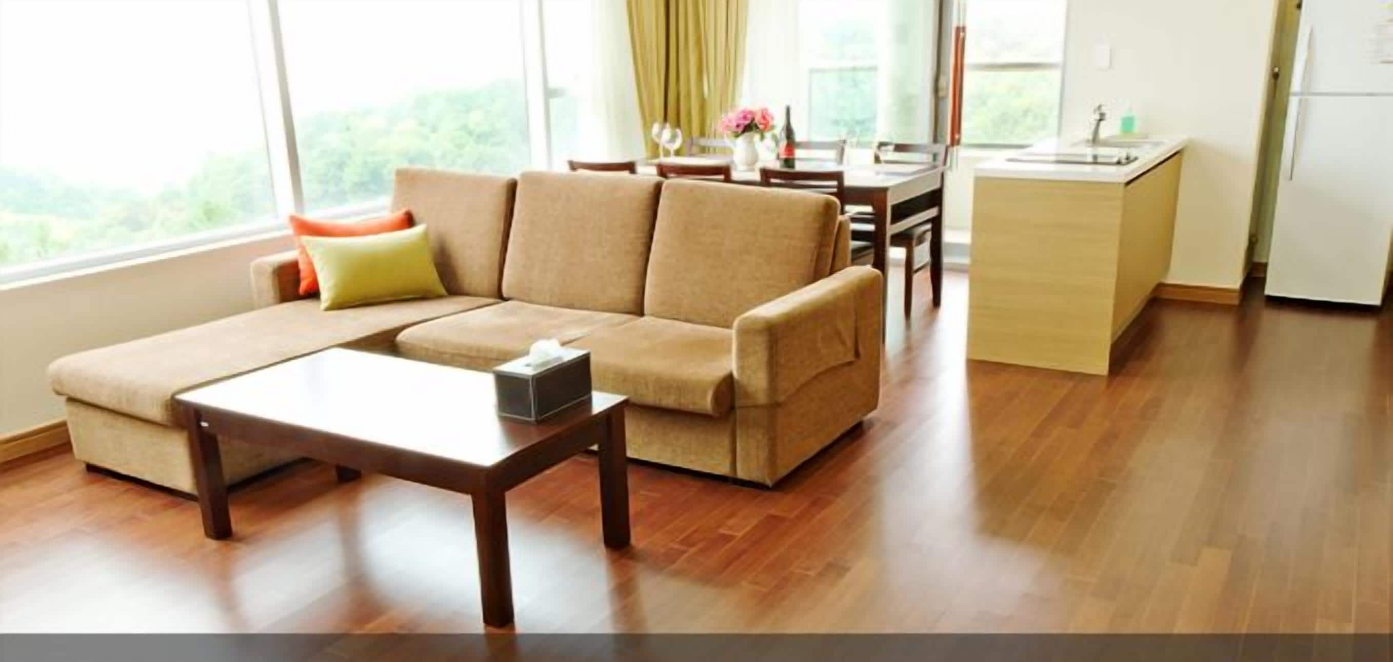 A modern living room with a sofa, a coffee table, and a kitchen area in the background.
