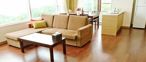 A modern living room with a sofa, a coffee table, and a kitchen area in the background.