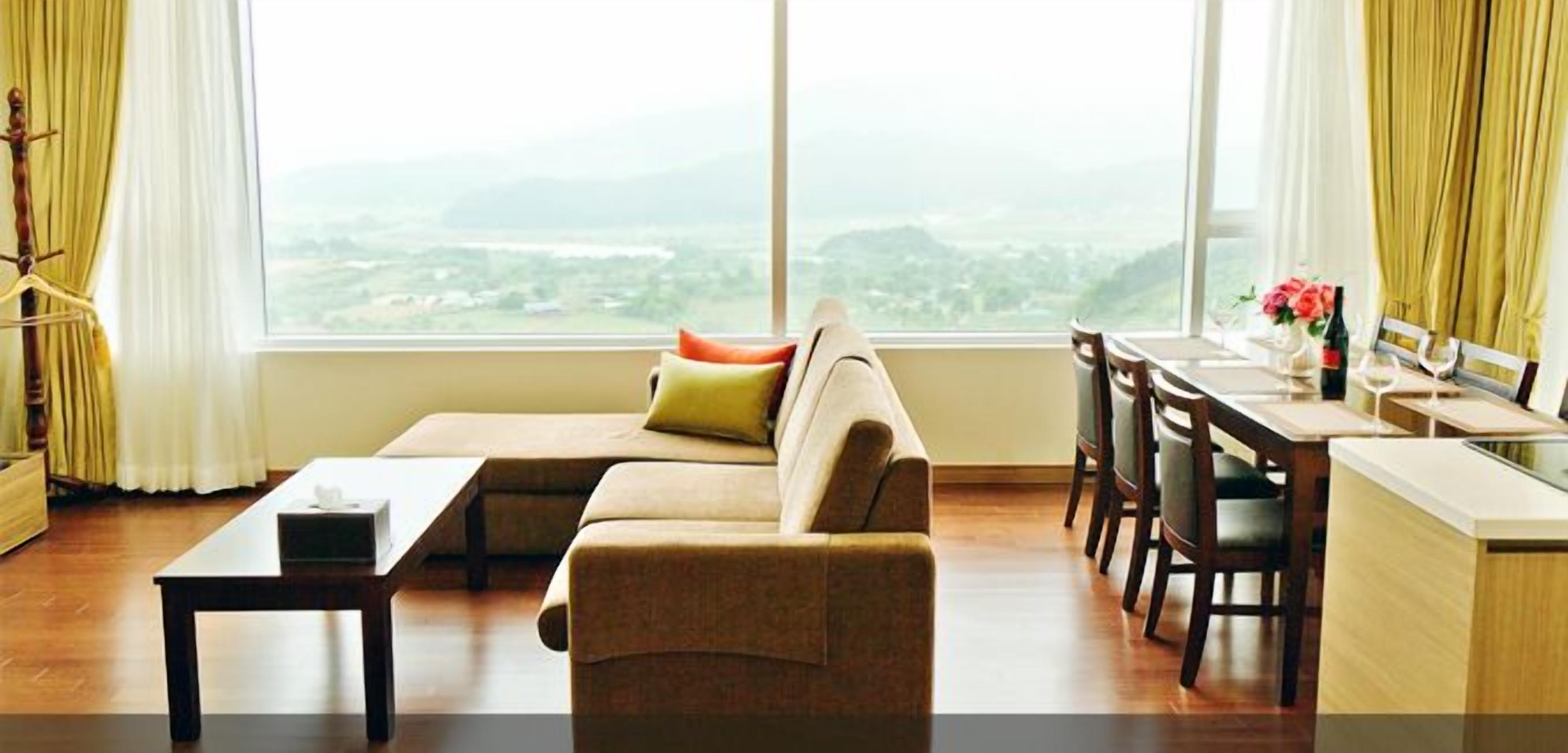 Ein modernes Wohnzimmer mit einer Couch, einem Esstisch und Stühlen. Durch große Fenster bietet sich ein Blick auf die Stadt.