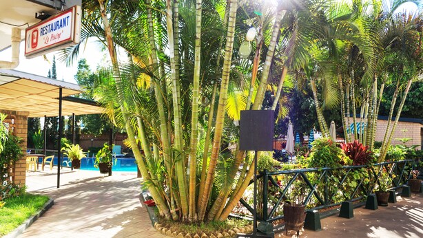 Un restaurante con letrero, mesas al aire libre y una zona de piscina.