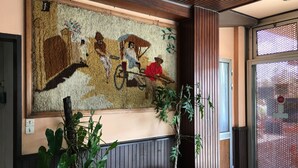 Un área de recepción con un gran mural de mosaico, plantas en macetas y un revestimiento de pared de madera.