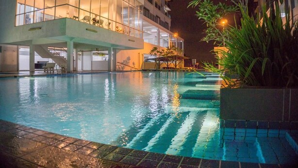 A swimming pool with a glass-bottomed section, surrounded by a building with a modern design and a balcony overlooking the pool. - Little Tree Homestay at Bangi Putrajaya (Kajang)
