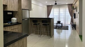 A modern kitchen with wooden cabinets, a built-in fridge, and a bar area with stools. - Little Tree Homestay at Bangi Putrajaya (Kajang)