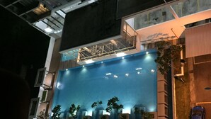 A modern building with a large illuminated facade, multiple balconies, and a parking area with a blue car. - Little Tree Homestay at Bangi Putrajaya (Kajang)