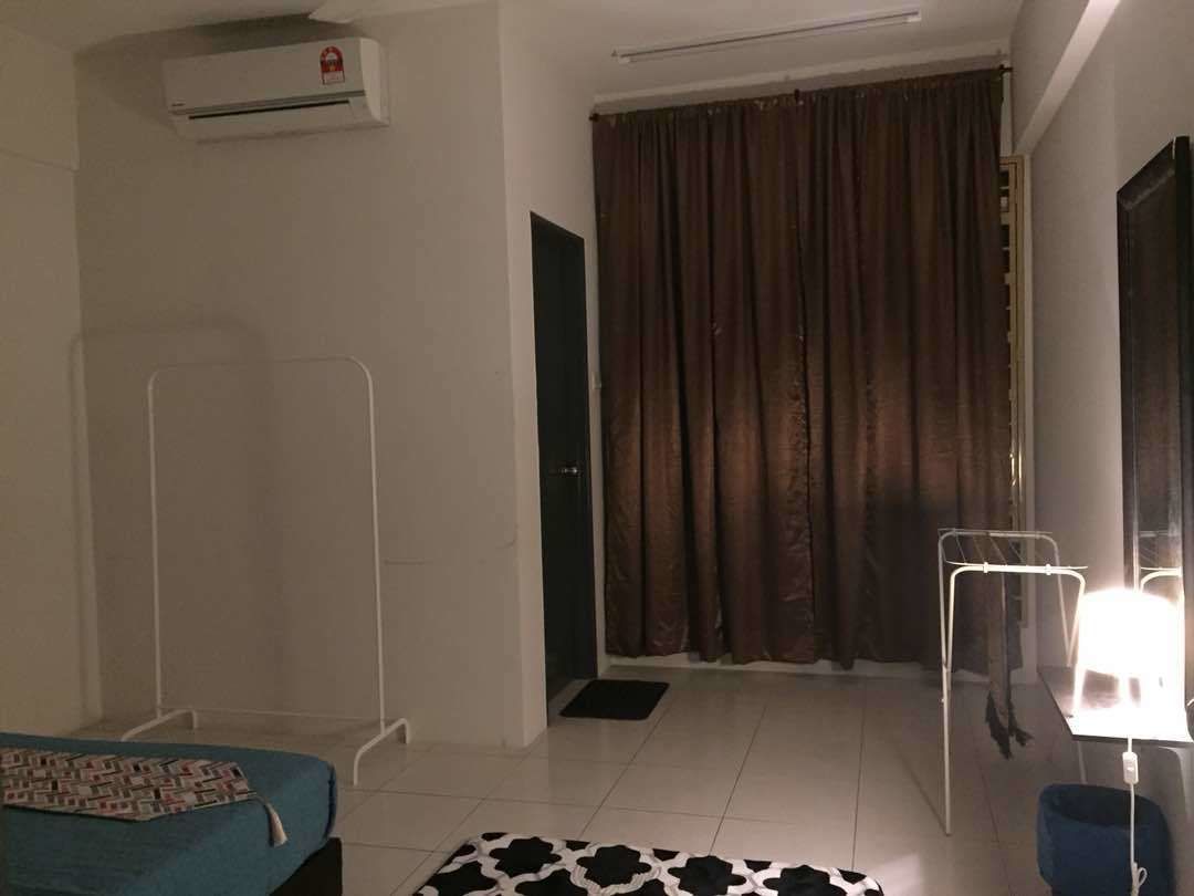 Una habitación de hotel con una cama, un escritorio con lámpara, aire acondicionado, una cortina y una puerta.