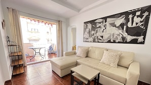 Una sala de estar con un sofá color beige, una mesa de centro y un cuadro abstracto grande en la pared.