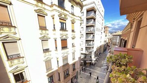 Un edificio de varios pisos con balcones, asientos al aire libre y un cielo despejado.