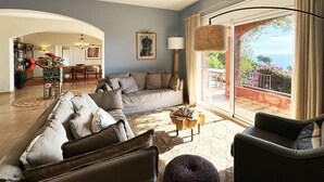 A spacious living room with a large sofa, a coffee table, and a view of the outdoors through a sliding glass door. - Holiday rental villa with swimming pool in Begur, Aiguablava (Begur)