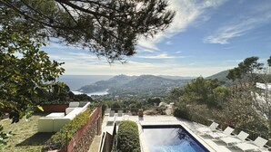 A pool area with lounge chairs, a view of the sea, and surrounding greenery. - Holiday rental villa with swimming pool in Begur, Aiguablava (Begur)