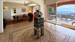 A spacious living area with a large, intricately designed rug, a dining table with chairs, and a view of the ocean through a glass door. - Holiday rental villa with swimming pool in Begur, Aiguablava (Begur)