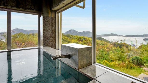 Una piscina interior moderna con vistas a un paisaje montañoso y un cuerpo de agua.