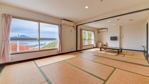 Una habitación con esteras de tatami, una mesa de tatami, un televisor y vistas a una montaña y árboles otoñales.