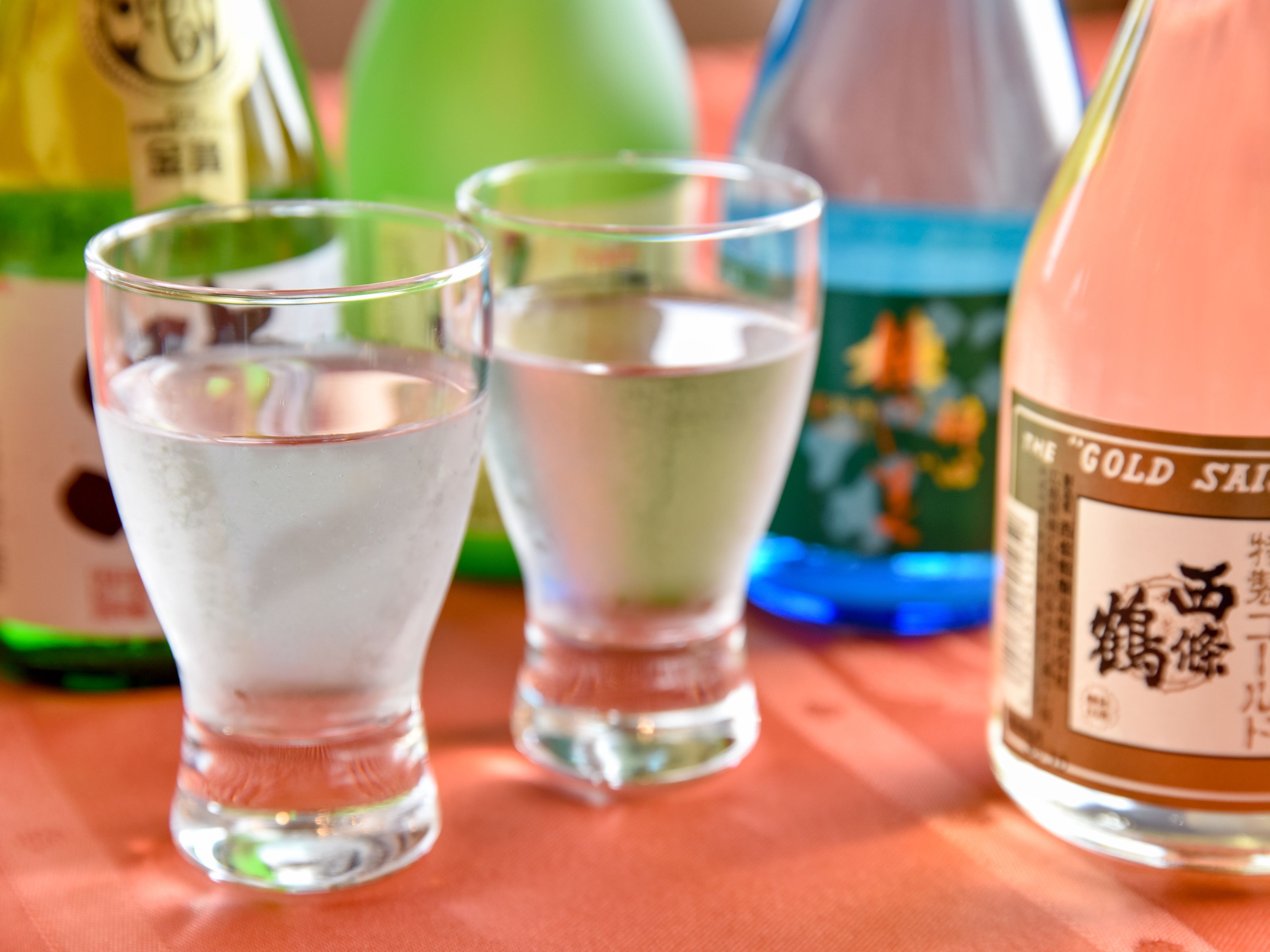 Three glasses of water and a bottle of Gold Sau.