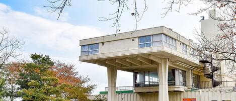 Un edificio con un diseño arquitectónico distintivo y un voladizo sobresaliente sostenido por columnas.