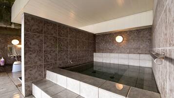 A modern bathroom with a large bathtub, tiled walls, and a step leading into the tub.