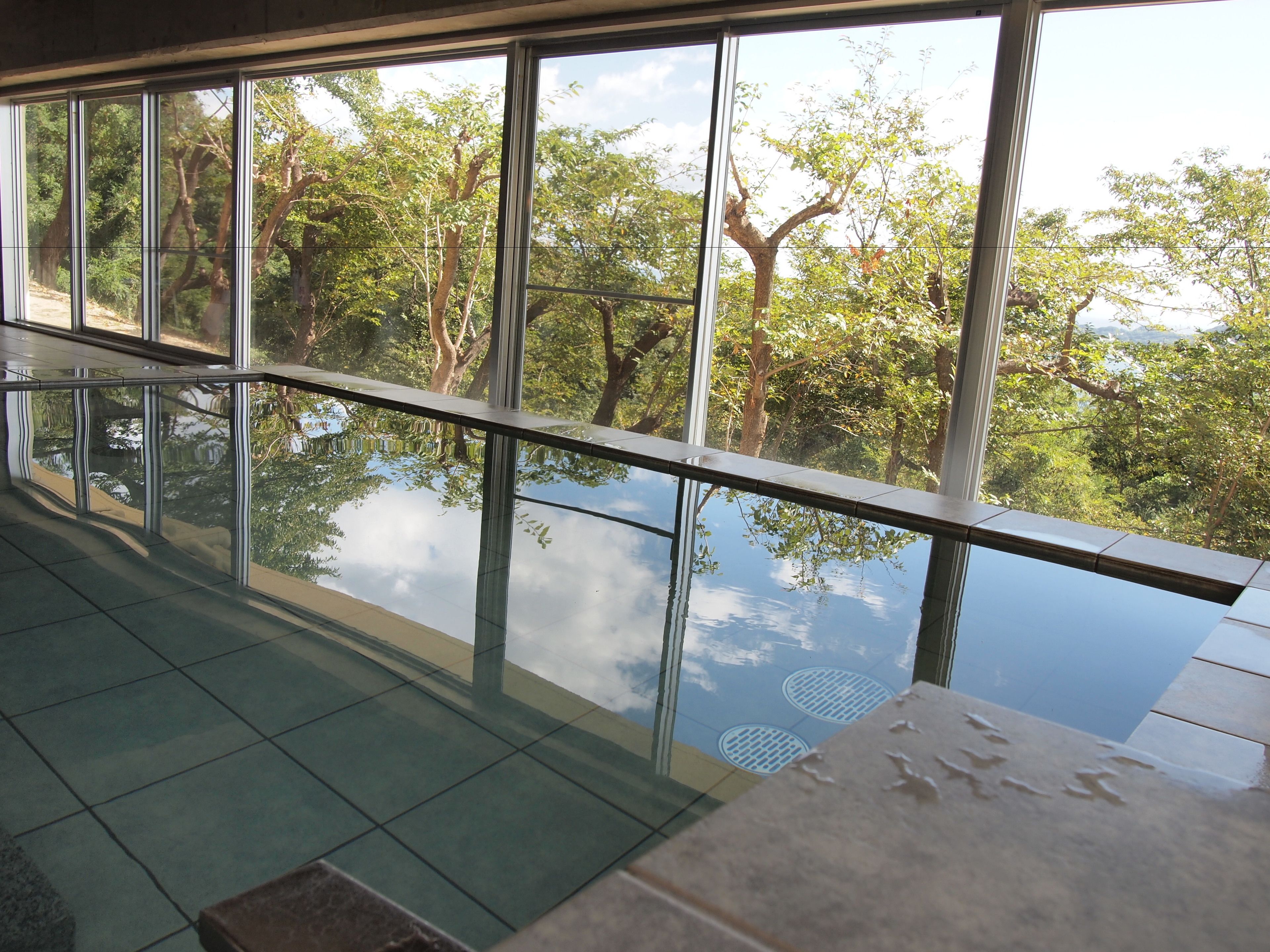 A modern interior with large windows offering a view of a lush, green landscape.